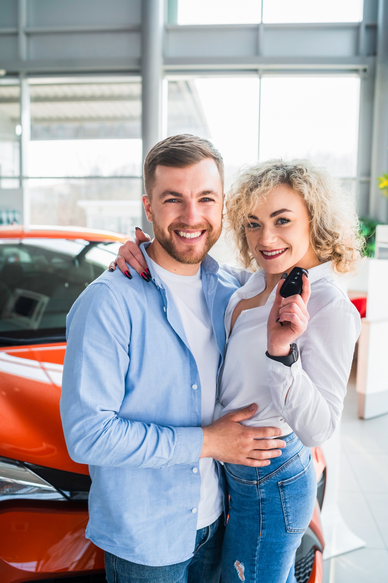Happy couple in car dealership on the background of their new car
