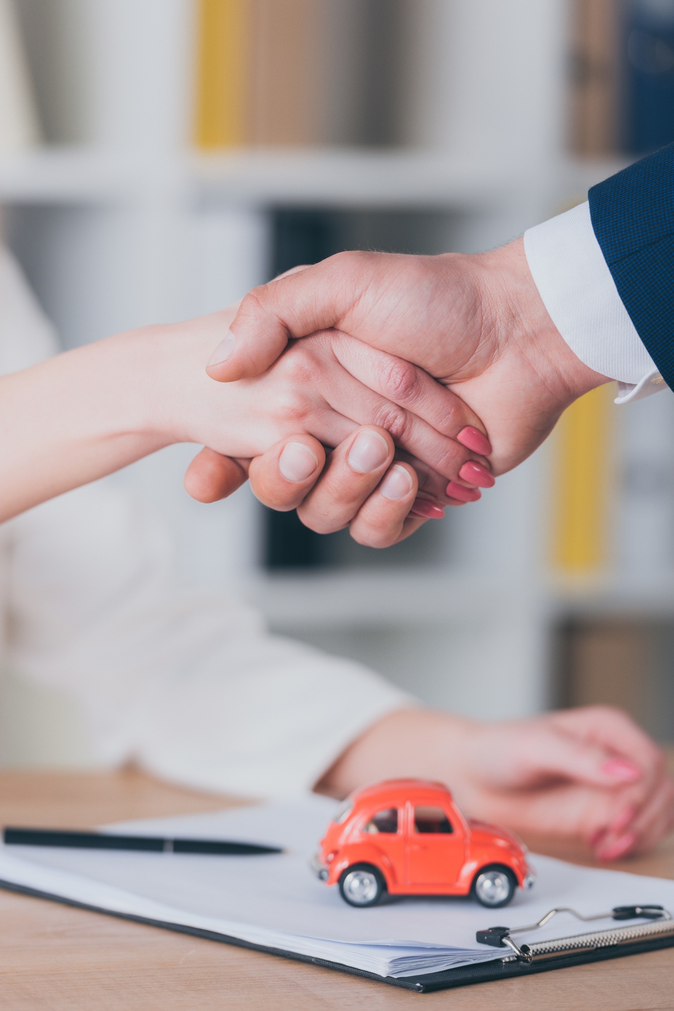 partial view of realtor shaking hands with customer near house model in office